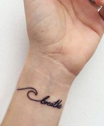Just breathe” tattoo on the wrist.